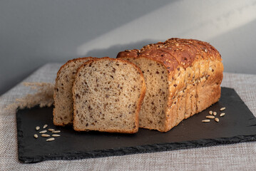 Rye bread with seeds lies on a dark board on a light table. My home bakery. Organic whole grain bread. Bio Dinkel Brot. Healthy bread. complex carbohydrates. health diet. Healthy breakfast.