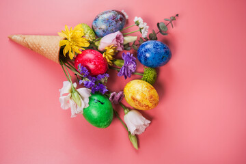 Beautiful bouquet of spring flowers and easter eggs in ice cream cone on pink background. 