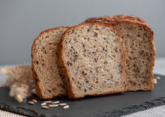 Rye bread with seeds lies on a dark board on a light table. My home bakery. Organic whole grain bread. Bio Dinkel Brot. Healthy bread. complex carbohydrates. health diet. Healthy breakfast.