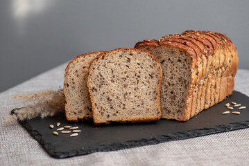 Rye bread with seeds lies on a dark board on a light table. My home bakery. Organic whole grain bread. Bio Dinkel Brot. Healthy bread. complex carbohydrates. health diet. Healthy breakfast.