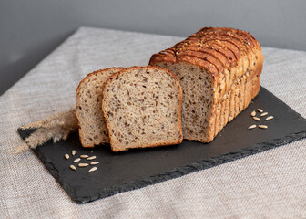 Rye bread with seeds lies on a dark board on a light table. My home bakery. Organic whole grain bread. Bio Dinkel Brot. Healthy bread. complex carbohydrates. health diet. Healthy breakfast.