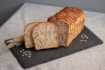 Rye bread with seeds lies on a dark board on a light table. My home bakery. Organic whole grain bread. Bio Dinkel Brot. Healthy bread. complex carbohydrates. health diet. Healthy breakfast.