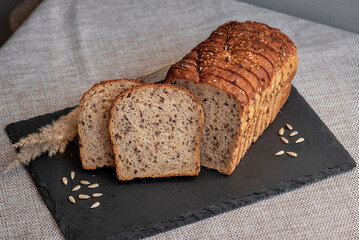 Rye bread with seeds lies on a dark board on a light table. My home bakery. Organic whole grain bread. Bio Dinkel Brot. Healthy bread. complex carbohydrates. health diet. Healthy breakfast.