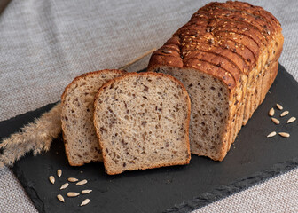 Rye bread with seeds lies on a dark board on a light table. My home bakery. Organic whole grain bread. Bio Dinkel Brot. Healthy bread. complex carbohydrates. health diet. Healthy breakfast.
