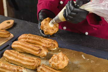 Filling freshly baked eclairs with custard