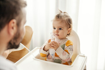 A sick little girl is using inhalator by her own. - obrazy, fototapety, plakaty