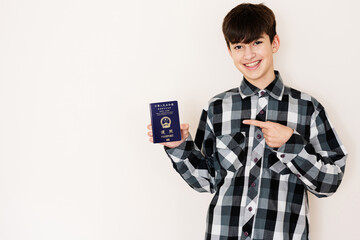 Young teenager boy holding Hong Kong passport looking positive and happy standing and smiling with...
