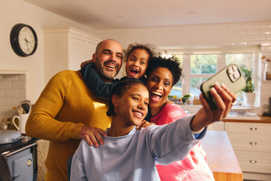 Teen girl taking selfie on phone with happy smiling family