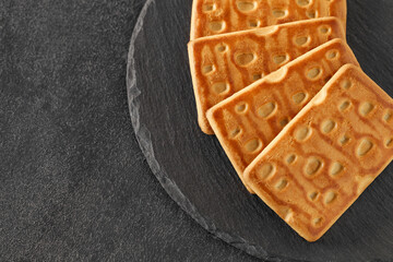 Rectangular sweet crumbly cookies, on slate stone plate round, dark background, top view, selective focus