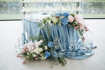 Wedding ceremony. Presidium for the newlyweds, decorated with candles and vases with blue and pink natural flowers such as eustoma, hydrangea, roses. Floristic concept