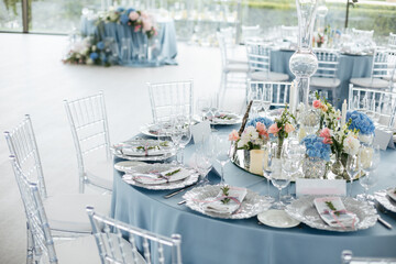Served wedding table with decorative fresh pink, blue flowers and candles. Celebration details....