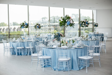 Served wedding table with decorative fresh pink, blue flowers and candles. Celebration details. Wedding decoration and decor, floristic concept
