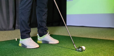 Professional male golfer playing golf indoors in golf simulator closeup