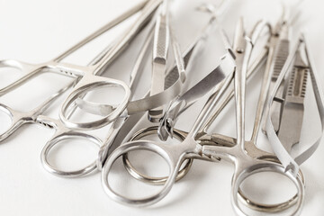 Surgical metal instruments, on white background, clamps, tweezers, scissors, selective focus