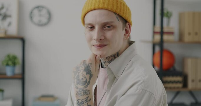 Slow motion portrait of successful young man in informal clothing smiling looking at camera in office room. Businessperson and employment concept.