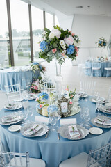 Served wedding table with decorative fresh pink, blue flowers and candles. Celebration details. Wedding decoration and decor, floristic concept