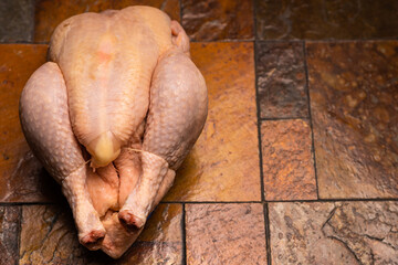 Whole whole chicken carcass on stone tile background.