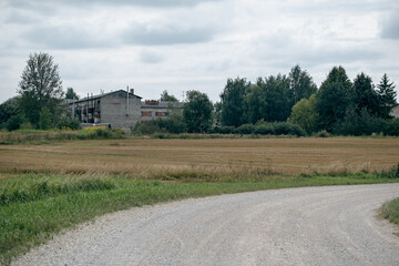 Obraz premium Rural landscape with a country road and a building in the background