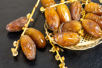 Close-up of Algerian royal dates on a wooden plate on a black background. Ramadan concept.