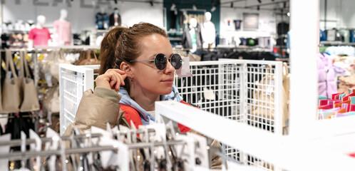Woman trying on sunglasses in store of apparel and accessories.
