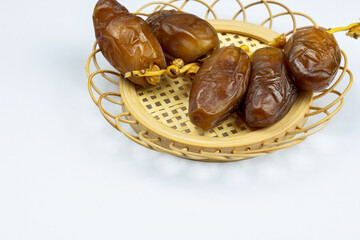 Close-up of Algerian royal dates on a wooden plate on a white background. Ramadan concept.