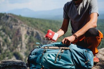 Take a first-aid kit in a backpack on a trip, a hand holds a first aid kit against the background...