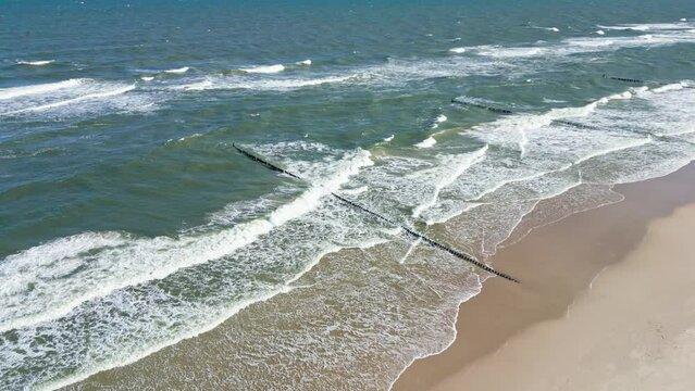 Rough Baltic Sea. Waves crashing against a wooden breakwater on the beach. Drone footage