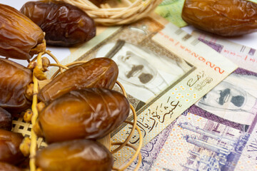Close-up of Algerian royal dates on a wooden plate. Saudi Arabia Money Banknotes. Ramadan concept.