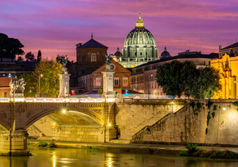 Victor Emmanuel bridge over Tiber river with St. Peter's cathedral dome in Vatican at night, Rome, Italy