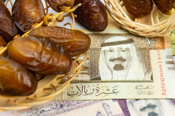 Close-up of Algerian royal dates on a wooden plate. Saudi Arabia Money Banknotes. Ramadan concept.