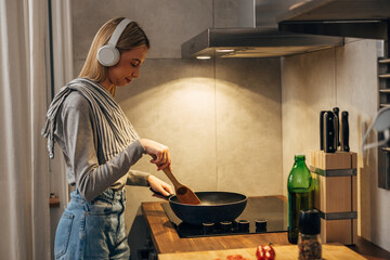 Side view of a young blonde woman cooking