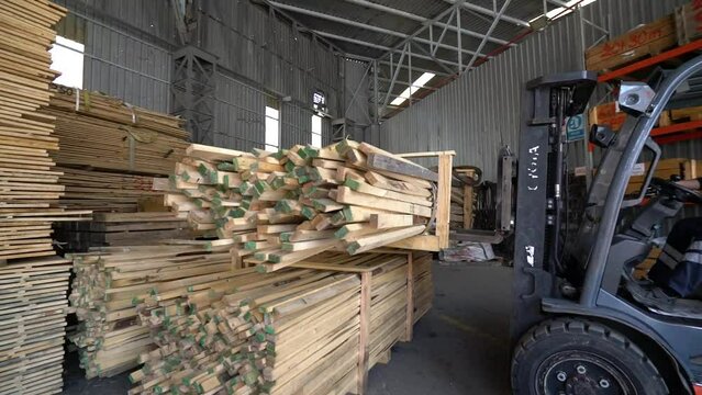 Forklift transports timber in and out of warehouse as vertical lifter