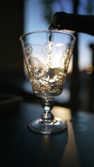 Pouring white wine on glass during sunset time outside. Slow motion shot of serving alcoholic beverage in Vertical Video