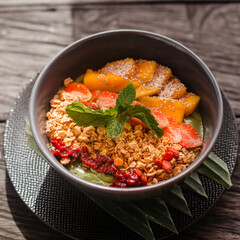 Natural granola with berries and fruits in a round plate. Top view of the smoothie bowl on a wooden table