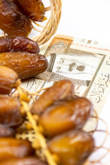Close-up of Algerian royal dates on a wooden plate. Saudi Arabia Money Banknotes. Ramadan concept.