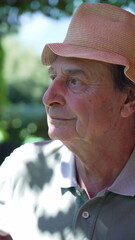 Portrait of a happy senior man close up face smiling at camera. One mature older male person in 70s wearing hat during summer day outdoors in Vertical Video