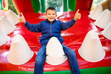 Fototapeta na wymiar Happy boy having a lots of fun on a colorful inflate castle