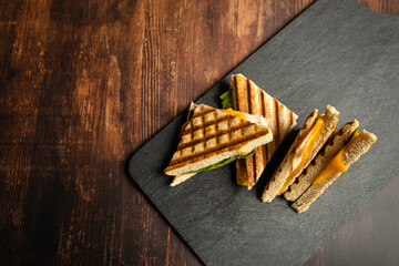 sandwiches with cheese and ham and salad on black slate