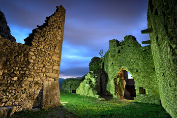 The portal of the mysterious medieval walls of Corno castle at night. Lenzima, Isera, Vallagarina,...