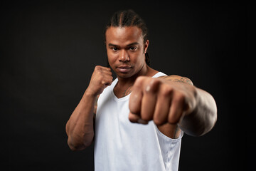 portrait of African-American athlete man boxing on black background