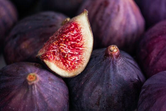 Fresh slice of fig lying on a heap of ripe figs. Heap of tasty organic figs