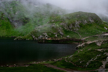 Fototapeta premium Balea Lac, Transfagarasan Romania fog covered lake during green summer