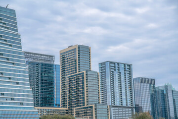 View of modern buildings with glass exterior from Auditorium Shores Park- Austin, Texas. Cityscape view near Colorado River against the cloudy sky background.