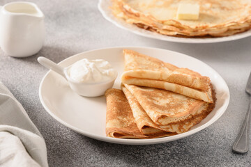 Russian thin pancakes or blini with butter on gray stone background. Close up.