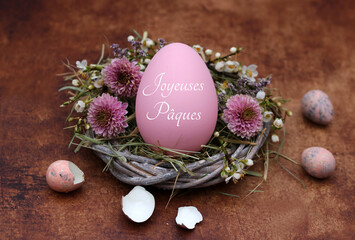 Oeuf de Pâques avec l'inscription Joyeuses Pâques dans un nid sur bois rustique.