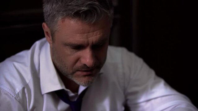 Close-up portrait of a businessman man in a white shirt with an untied tie, drinks alcohol, whiskey, scotch, sighs, received a false accusation, sad, upset, exhausted