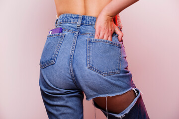 Woman wearing jeans view from behind. Female bottom in ripped denim pants, smart phone in pocket