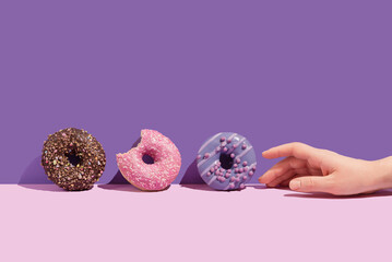 A hand with a tasty donuts on a color background