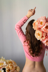 Young beautiful woman in pink crop top and bottomless. Girl with bouquet peonies