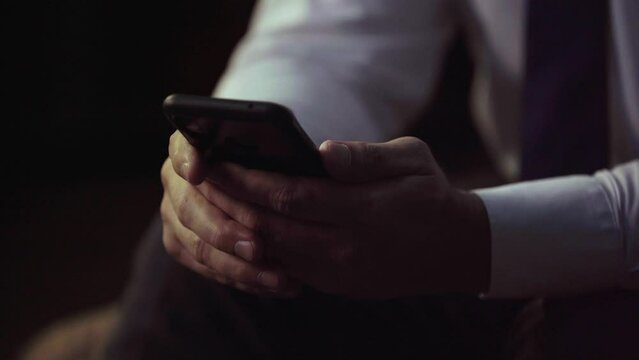 Close-up shot of man's hands, businessman in tie, holding phone, typing message, scrolling, close-up